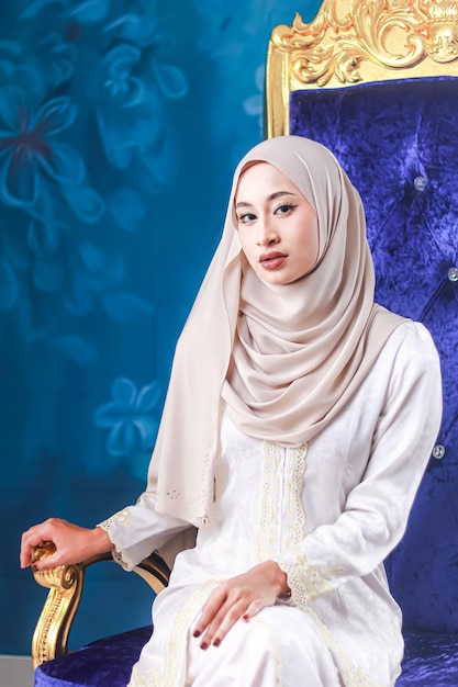 A woman in a white hijab and a blue wall behind her