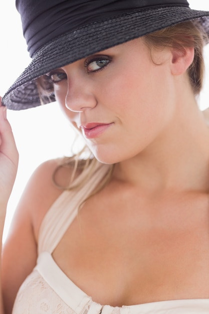 Woman in white holding black hat while smiling