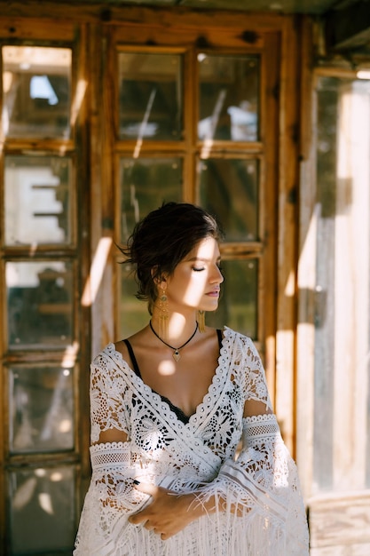 Woman in a white lace cape sits near an antique wooden door portrait