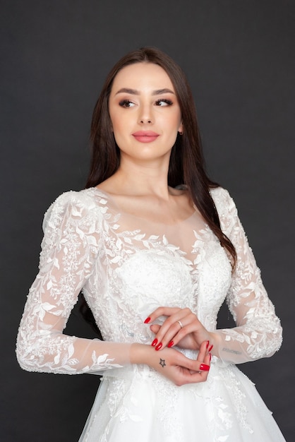 A woman in a white lace wedding dress with a tattoo on her hand