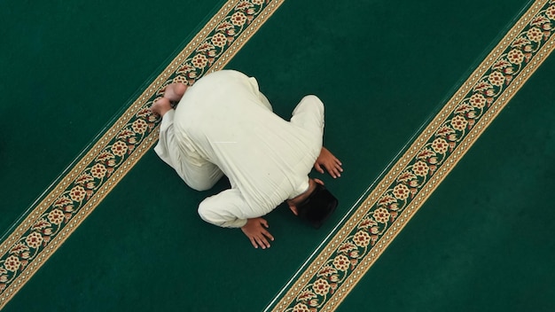 A woman in a white robe is doing a yoga pose on a green carpet.