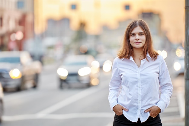 Woman in white shirt on background of traffic on city street