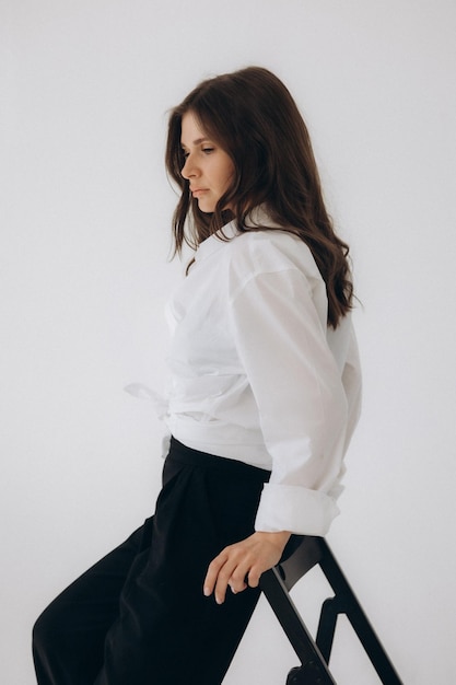 A woman in a white shirt and black skirt stands on a white background