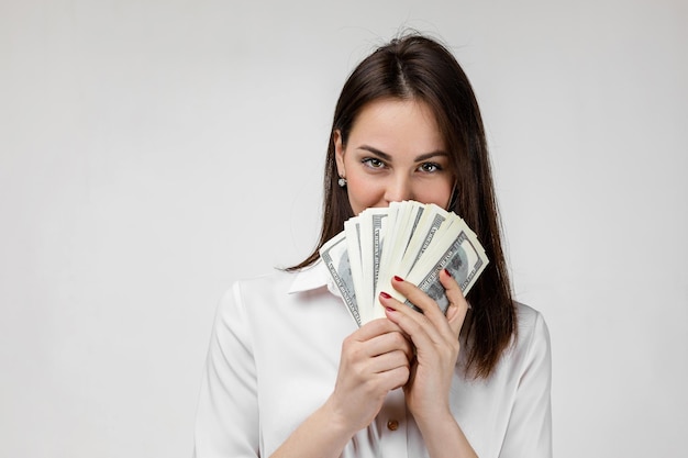 Woman in white shirt hiding behind bunch of money banknotes