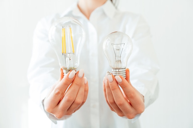 Woman in white shirt holding light bulb in hand