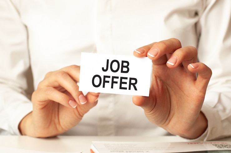 Woman in a white shirt holds a piece of paper with the text: job offer. business concept for companies