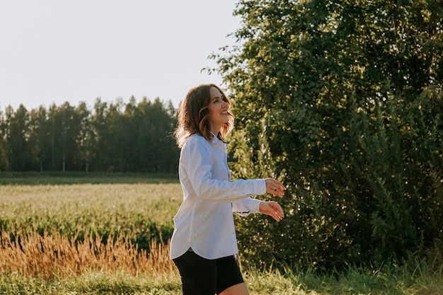 Woman in a white shirt on a natural background. Walk in the forest. Happy young woman