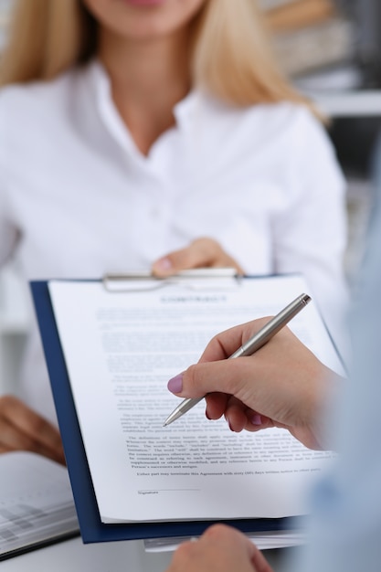 Woman in white shirt offering contract on clipboard