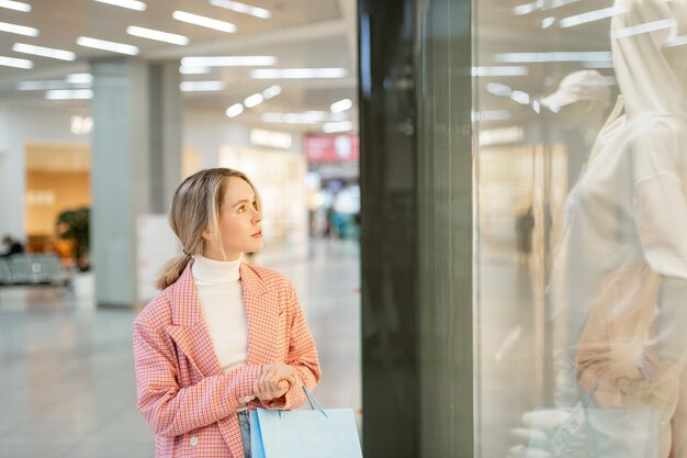 モールの大きなディスプレイのそばに立っている白いシャツを着た女性