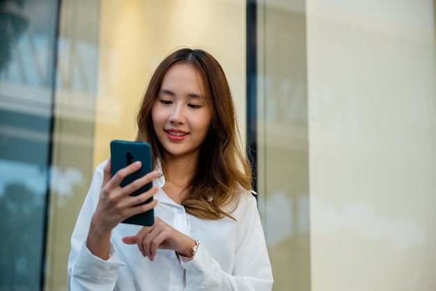 Photo a woman in a white shirt using her smartphone for business