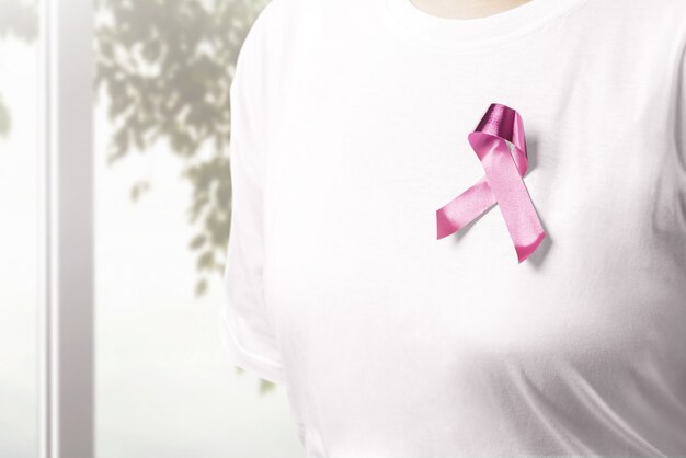 Photo woman in a white shirt with a pink ribbon with window