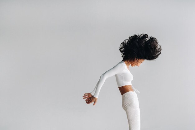 A woman in white sportswear is engaged in dynamic kali meditation in the yoga hall