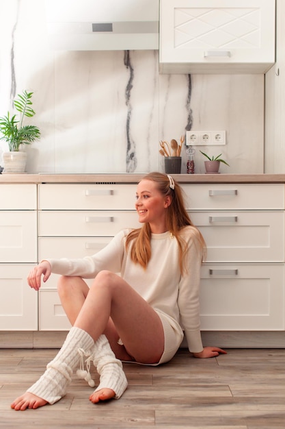 Woman in white sweater and stockings sitting on a floor