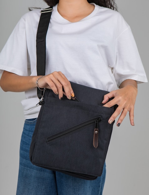 Woman in white t-shirt carry the casual bag on shoulder with active and easy gesture.