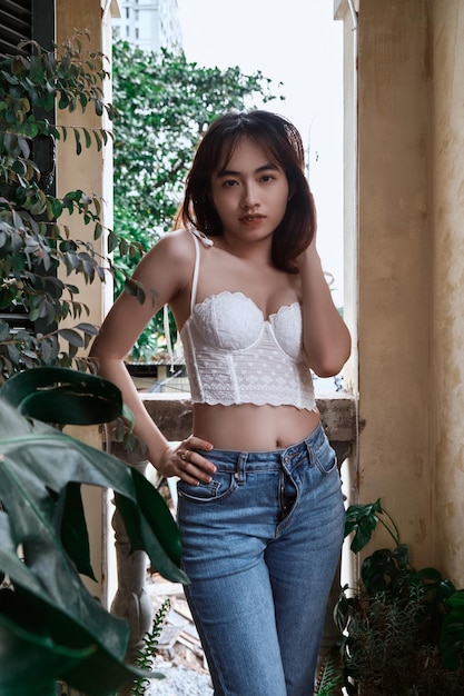 A woman in a white top and jeans stands on a balcony.