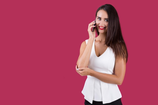 彼女の電話で話している白いトップスの女性