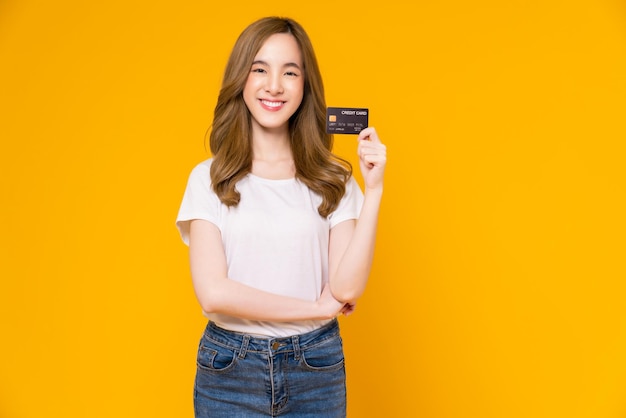 Photo woman in white tshirt and holding mockup credit card on yellow background