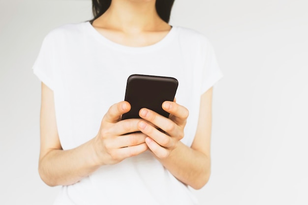 a woman in a white tshirt uses a smartphone