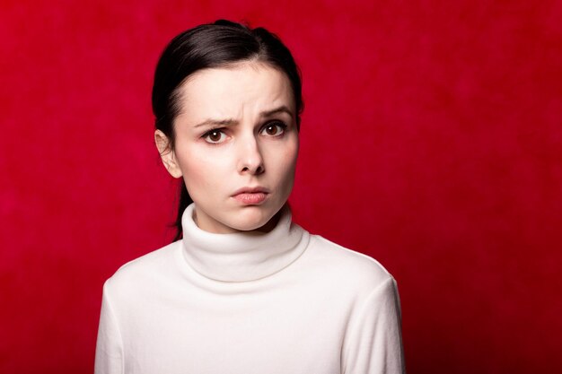 woman in a white turtleneck portrait on a red background