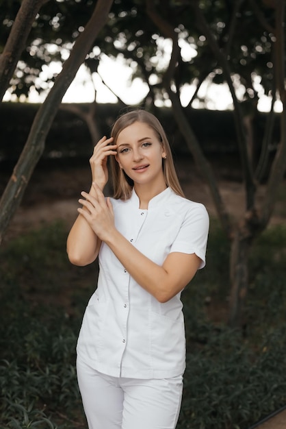 A woman in a white uniform stands in a forest