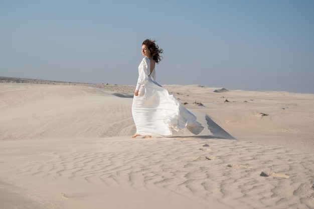 Woman in white waving dress in desert