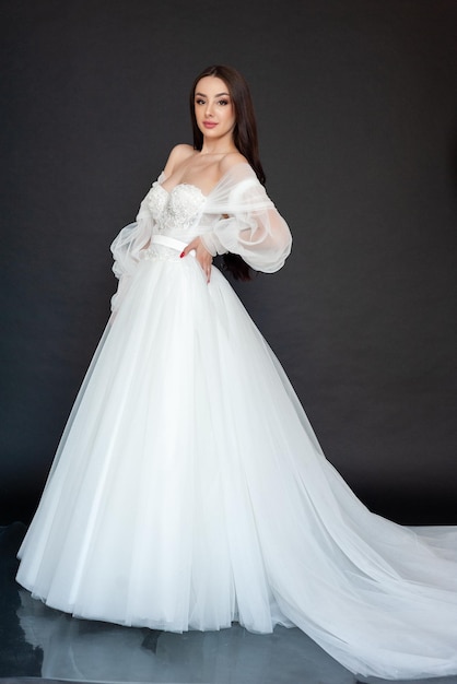 A woman in a white wedding dress with a long sleeved top and a long sleeved skirt.