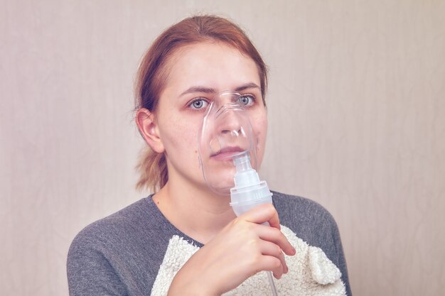 Woman, who has COPD, is doing inhalation with help of nebulizer chamber.