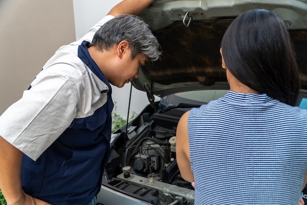 写真 車を所有している女性が立っていて、整備士を待っているのを探していますエンジンをチェックして原因を見つけてください