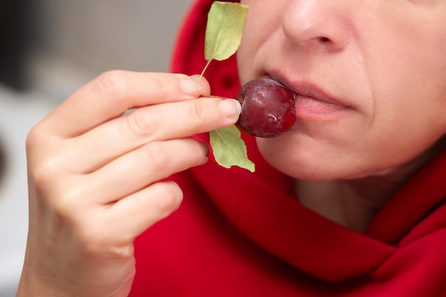 Una donna il cui viso non è visibile mangia una piccola mela selvatica rossa