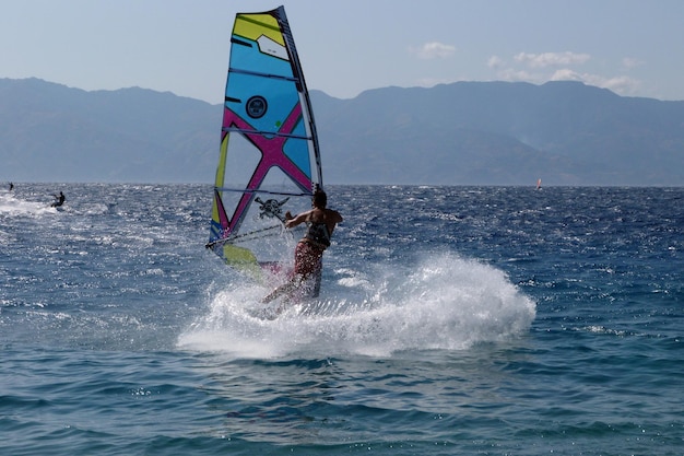 空に向かって海でウィンドサーフィンをしている女性
