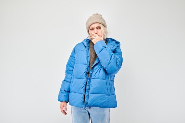 Woman in winter attire with pensive expression thinks chooses isolated on light background