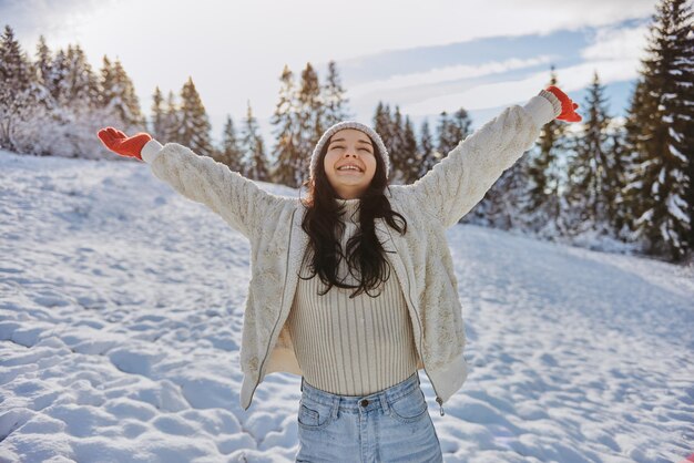 Woman in winter clothes raised hands outdoors in forest