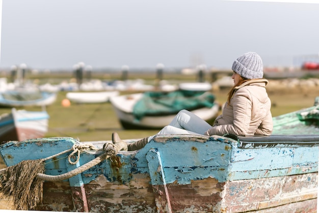 Woman in winter clothes sitting on a fishing boat