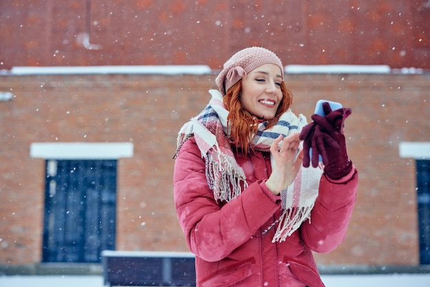 Женщина в зимней одежде с помощью мобильного телефона