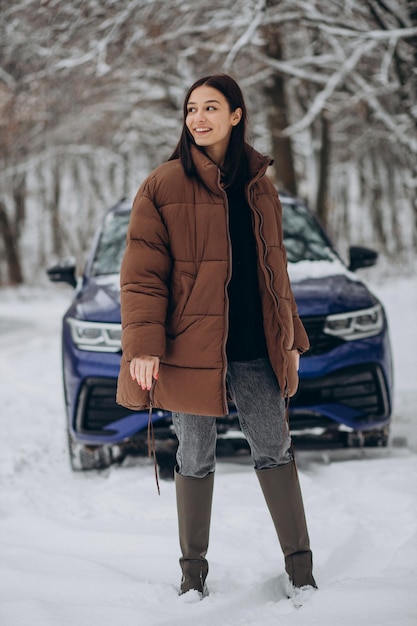 Woman in winter forest by her car