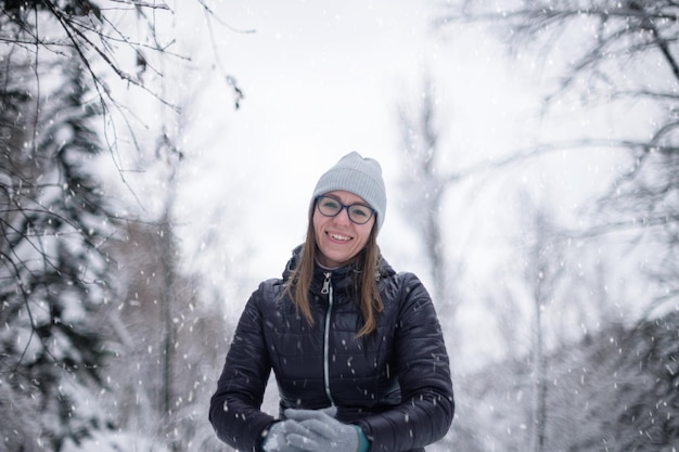 Woman in winter jacket walking in snowy winter forest snowy winter day