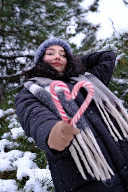 Woman in winter time holding two candy canes forming a heart Happy New Year Christmas time