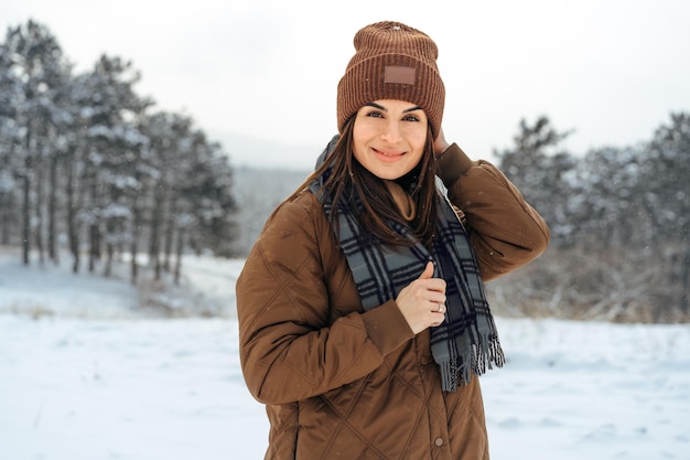 雪の降る冬の森を歩く冬の暖かいジャケットの女性