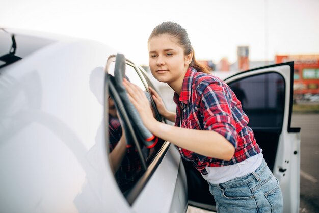 洗車後、女性が布で車を拭く