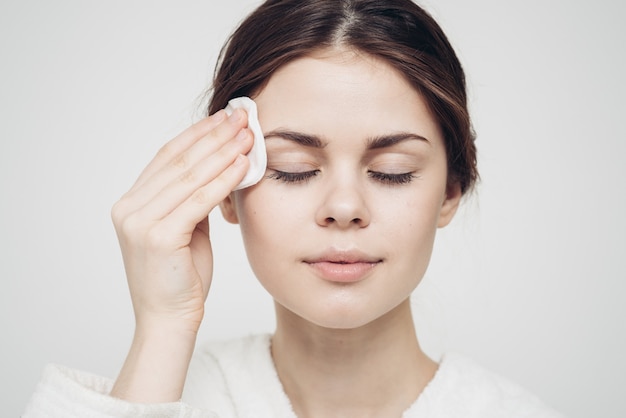 Woman wipes her face with a white soft sponge beauty care\
model