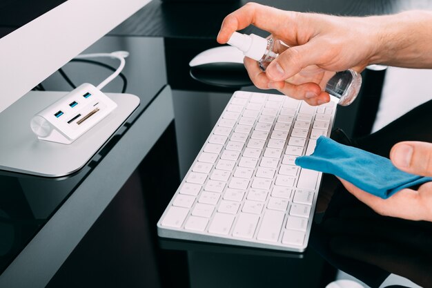 Woman Wiping Mobile Phone Screen With Sanitizer on wood