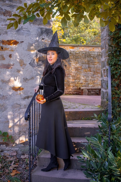 woman in a witch costume in an autumn forest or castle halloween