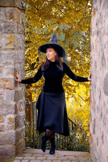 Foto donna in costume da strega in una foresta autunnale o in un castello di halloween