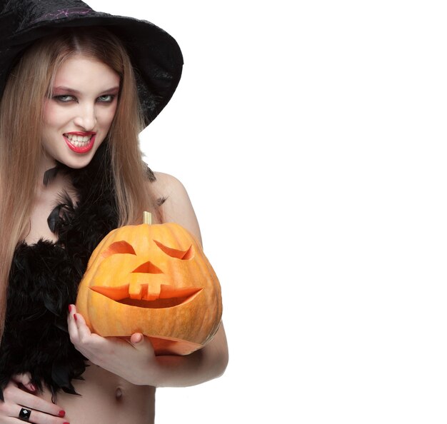 Woman in witch costume opens carved Halloween pumpkin and space for text