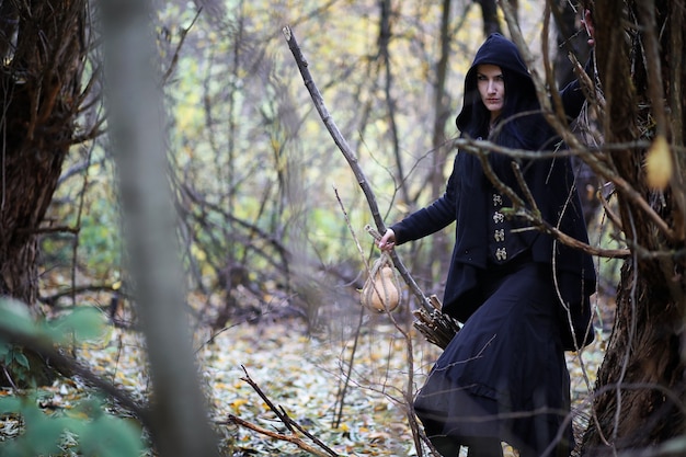 A woman in a witch suit in a dense forest on a ritual