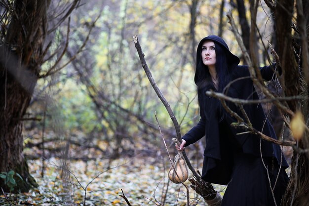 A woman in a witch suit in a dense forest on a ritual