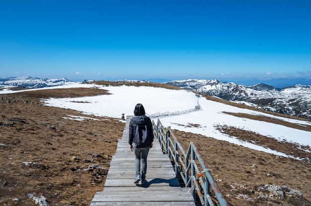 写真 バックパックを持つ女性は雪の山の上を歩く