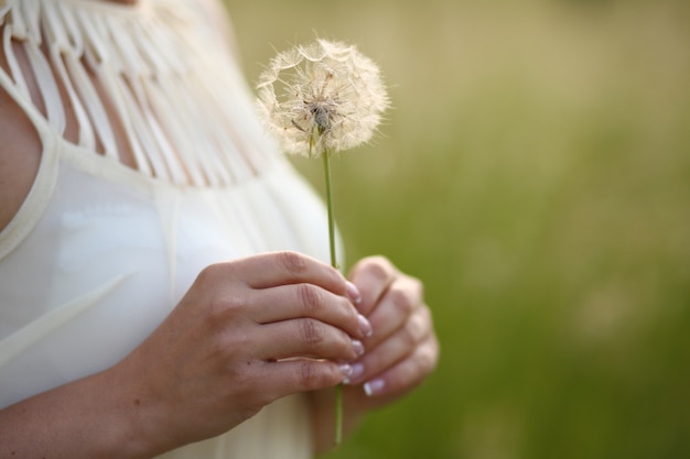 写真 彼女の手にタンポポを持つ女性