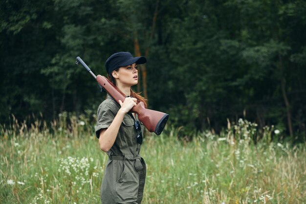 写真 肩に銃を持った女性 黒い帽子は狩の生活様式です 緑のオーバーオールクローズアップ