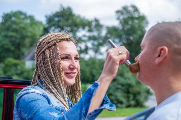 A woman with african braids applies powder to a man face with a powder brush copy space high quality photo